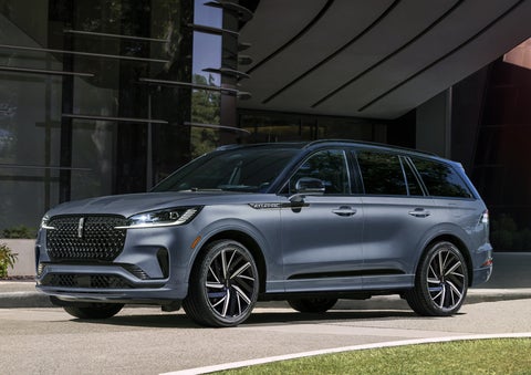 A gray 2025 Lincoln Aviator® SUV is parked outside a modern building showcasing the driver’s side of the vehicle. | Pugmire Lincoln of Marietta in Marietta GA