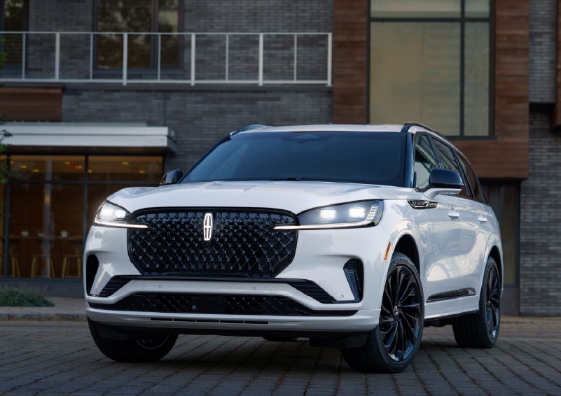 A 2026 Lincoln Aviator® Reserve model is shown with the available Jet Appearance Package parked near a restaurant. | Pugmire Lincoln of Marietta in Marietta GA