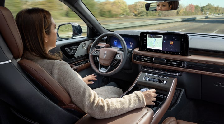 A 2026 Lincoln Aviator® SUV is being driven hands-free on a highway near a forest | Pugmire Lincoln of Marietta in Marietta GA