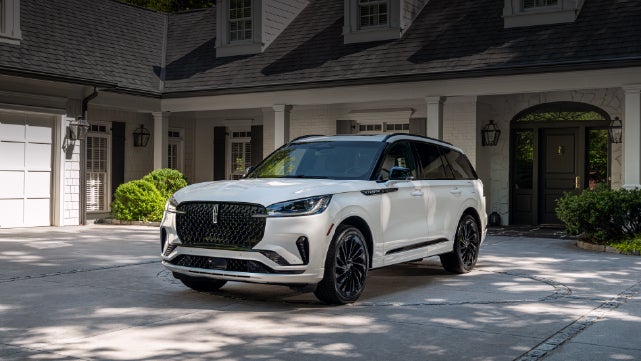 A white 2026 Lincoln Aviator® SUV is parked in the driveway of a luxury home. | Pugmire Lincoln of Marietta in Marietta GA