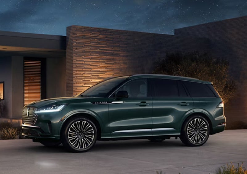 A green 2027 Lincoln Aviator® SUV is parked outside a contemporary home. | Pugmire Lincoln of Marietta in Marietta GA