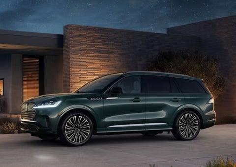 A green 2027 Lincoln Aviator® SUV is parked outside a contemporary home. | Pugmire Lincoln of Marietta in Marietta GA