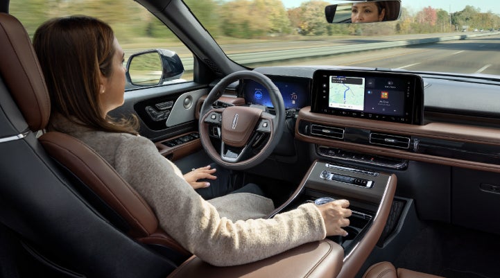 A 2027 Lincoln Aviator® SUV is being driven hands-free on a highway lined with trees. | Pugmire Lincoln of Marietta in Marietta GA