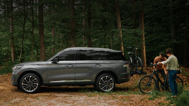 A father and son load e-bikes on a bike rack attached to a 2027 Lincoln Aviator® SUV. | Pugmire Lincoln of Marietta in Marietta GA