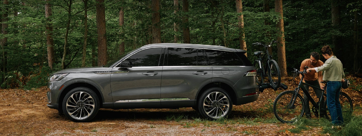 A father and son load e-bikes on a bike rack attached to a 2027 Lincoln Aviator® SUV. | Pugmire Lincoln of Marietta in Marietta GA